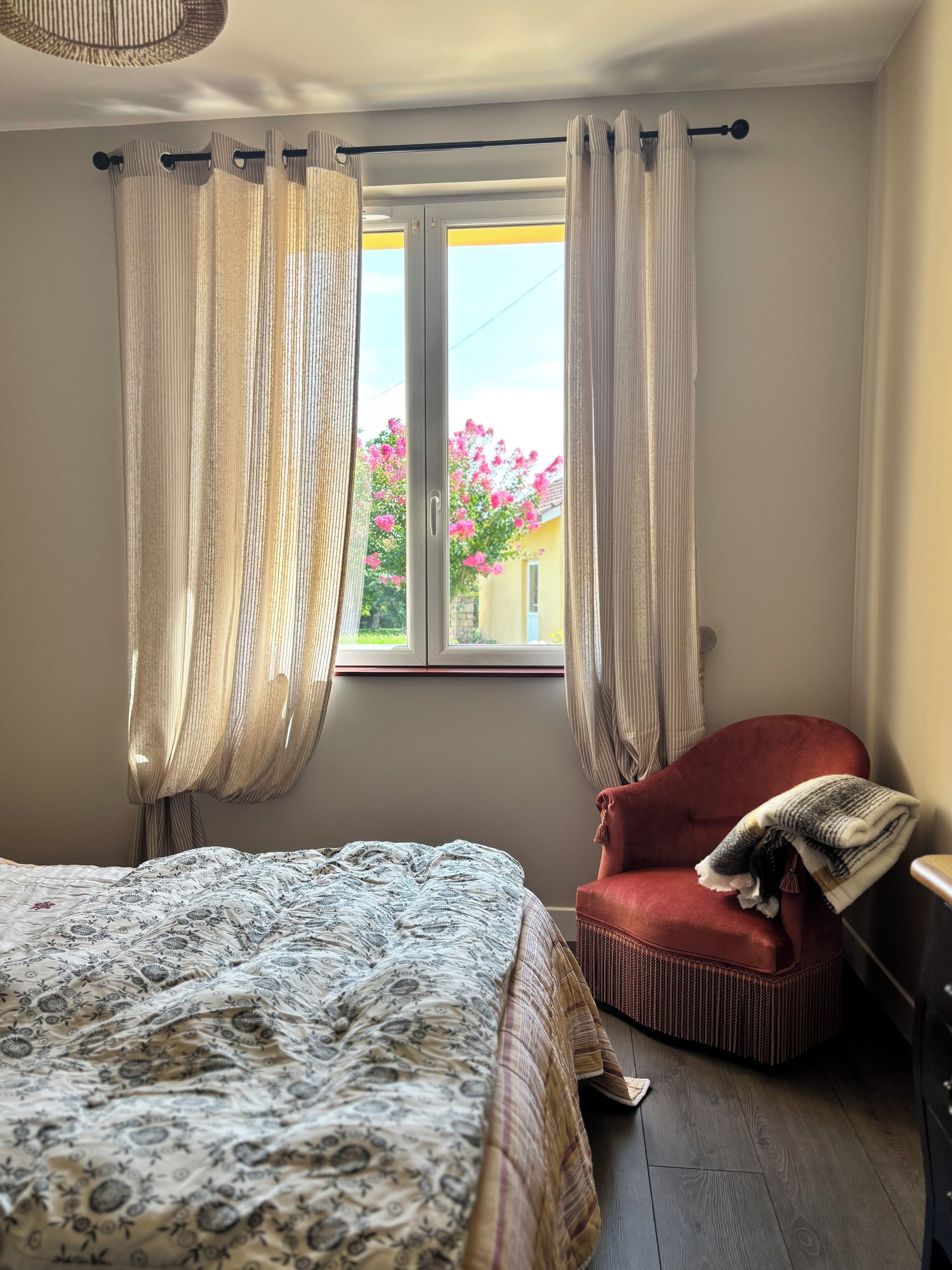Une chambre à coucher avec un lit, une chaise et une fenêtre avec des rideaux.
