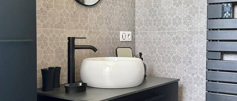 A bathroom with a modern sink, a mirror, and a towel rack.