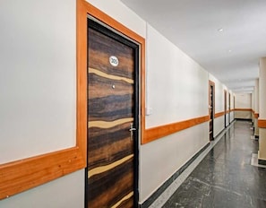Ein Hotelkorridor mit Holztüren, darunter die Nummer 305, und einem Marmorboden.