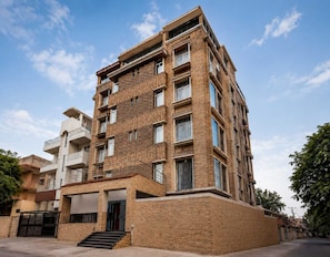 A multi-story residential building with a brick facade, balconies, and a gated entrance.