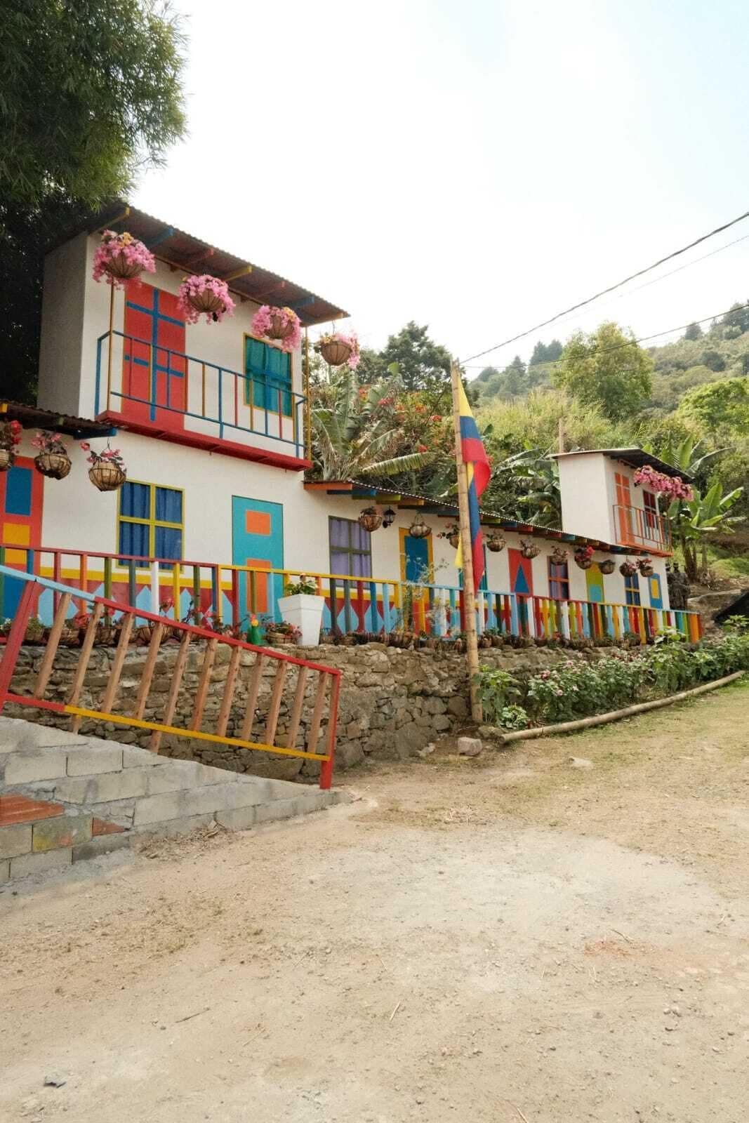 A two-story building with colorful walls and balconies adorned with hanging flower baskets.
