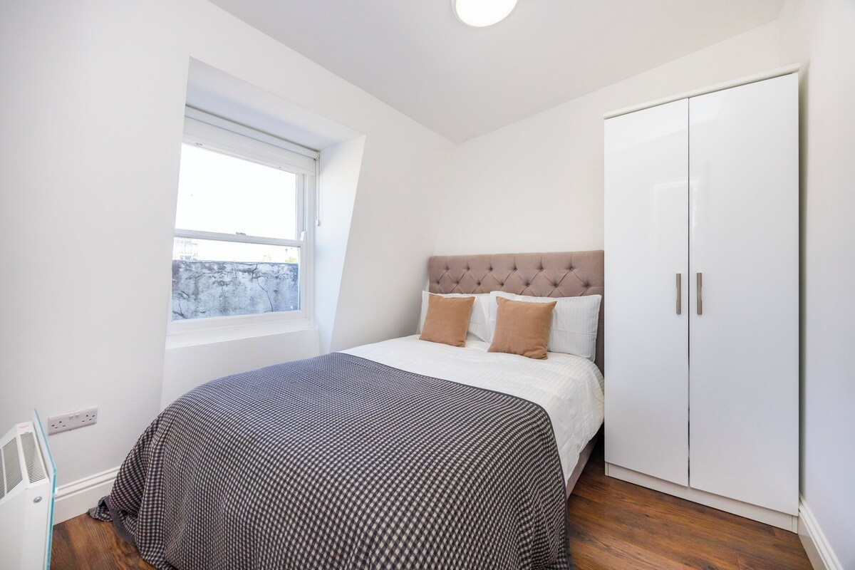 A bedroom with a bed, a wardrobe, a window, and a radiator.