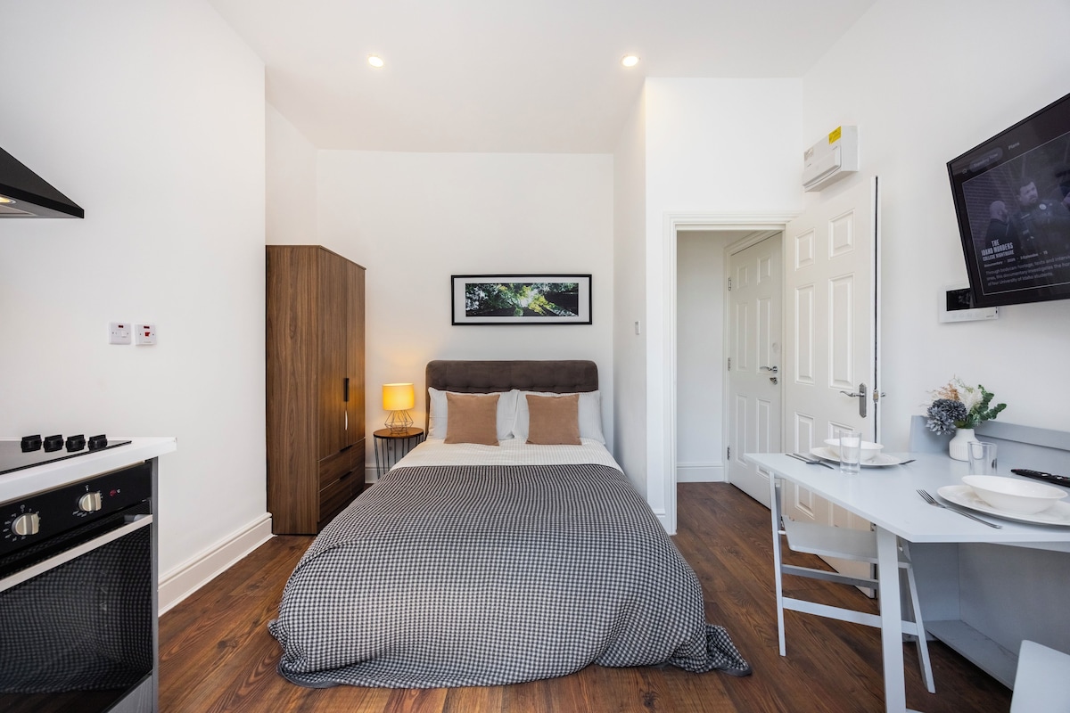 A modern bedroom with a bed, a desk, and a television.