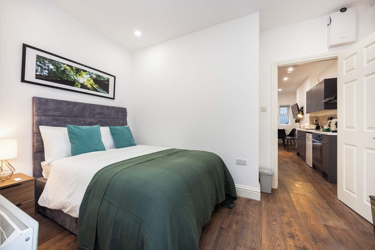 A bedroom with a bed, bedside table, and a wall-mounted picture.