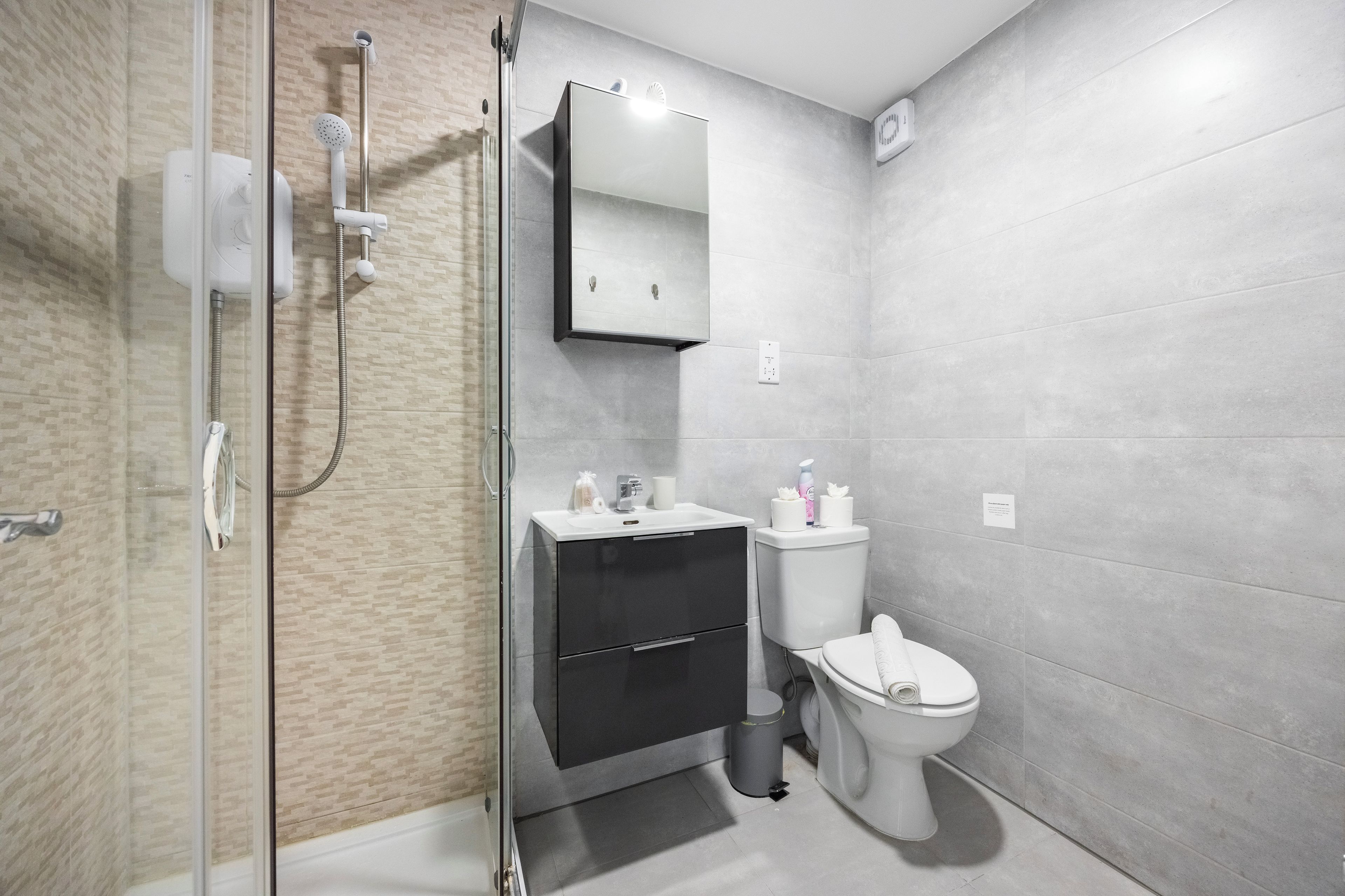 A modern bathroom with a glass shower enclosure, a white toilet, and a black vanity.