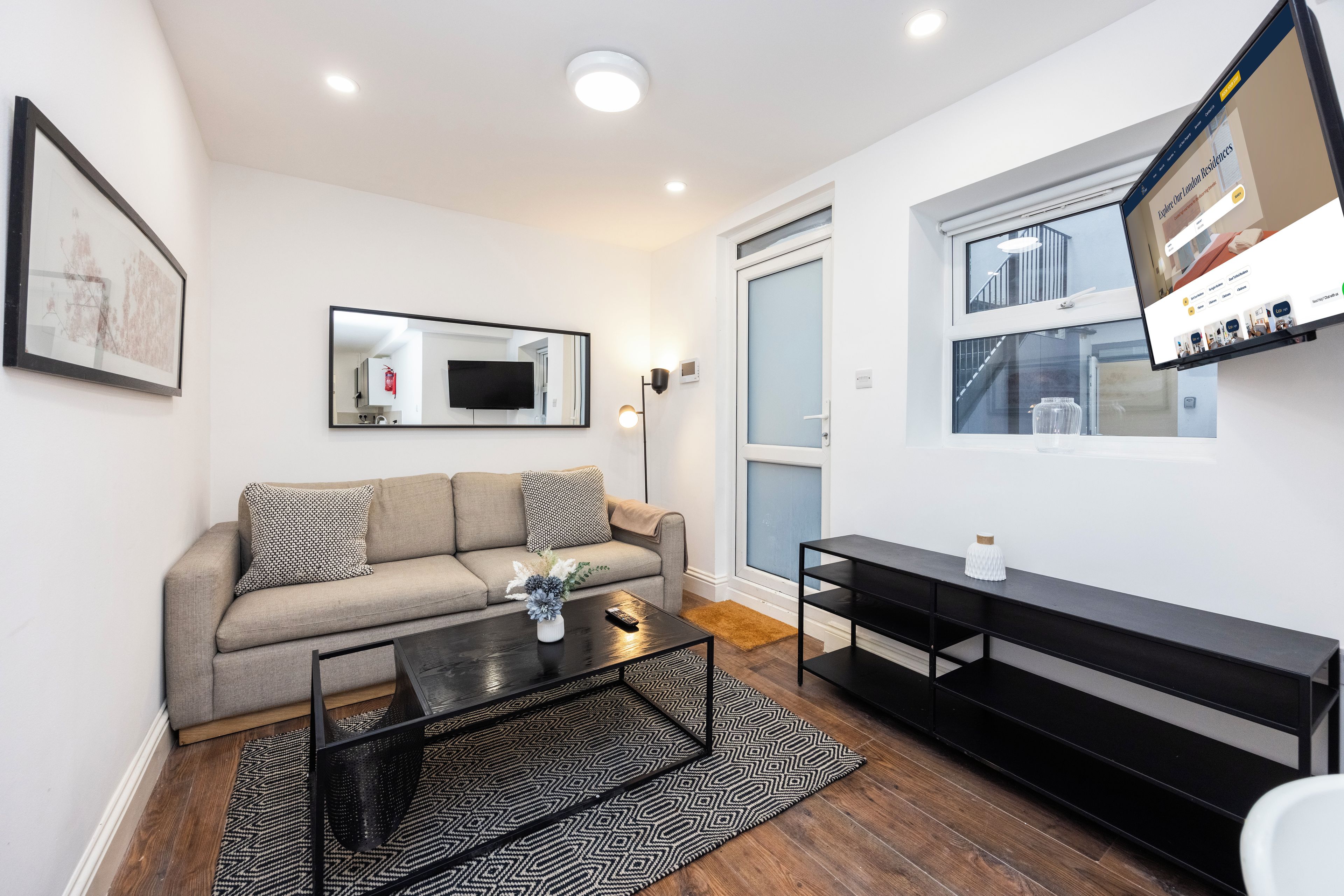 A modern living room with a sofa, coffee table, and a flat-screen TV mounted on the wall.