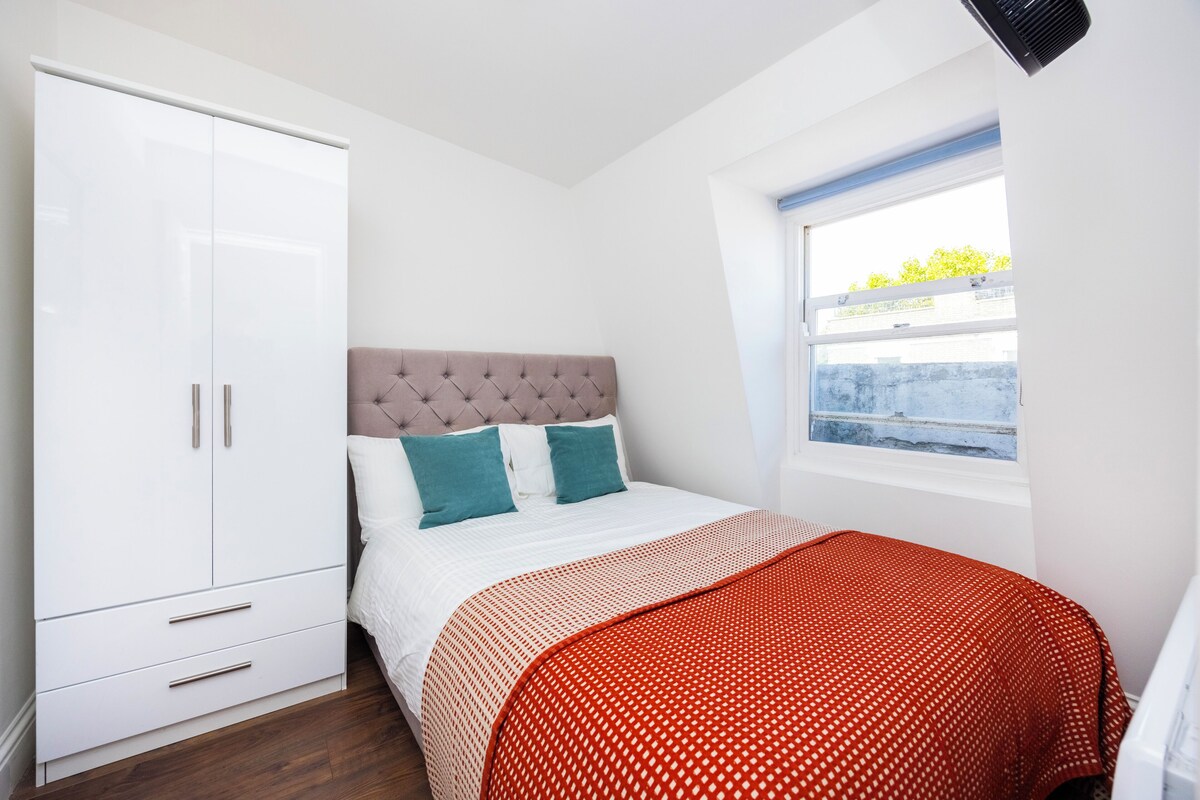 A bedroom with a bed, a wardrobe, and a window.
