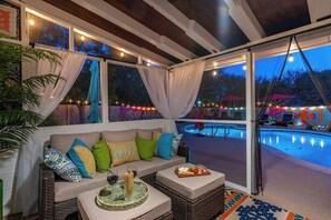 A cozy indoor seating area with a view of an outdoor pool and patio. - NEW! Pool, HotTub, Pickleball, Mini Golf + Theater (San Antonio)
