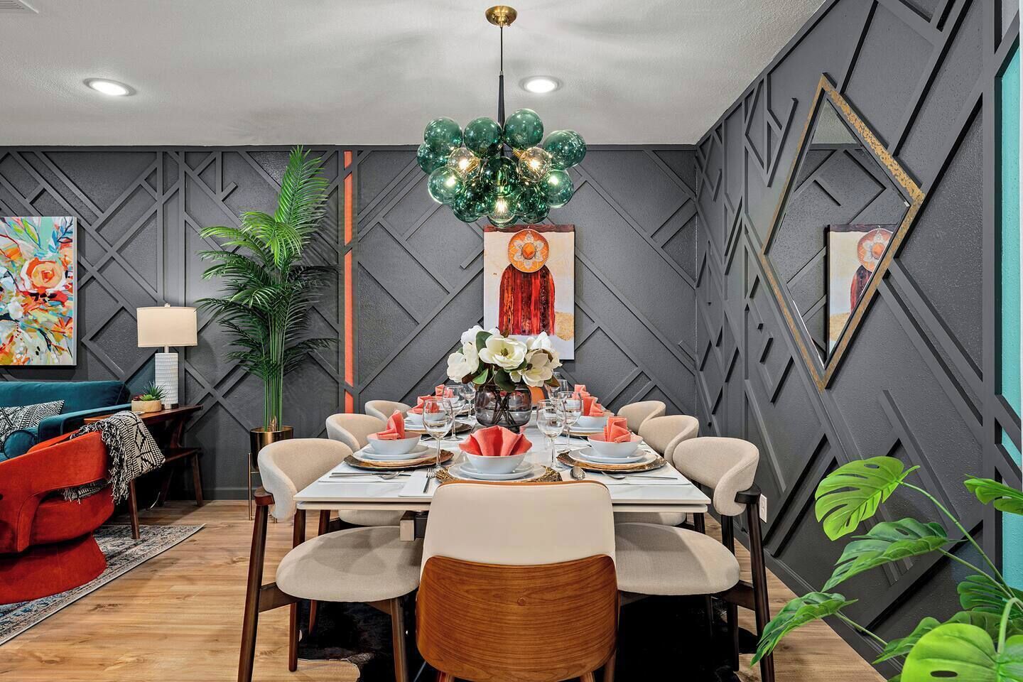 Un espace repas agrémenté d’un motif géométrique sur le mur, d’un lustre et d’une table dressée pour six personnes.