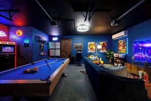 A pool table with a neon sign, a sofa, a TV, and a poster on the wall. - Heated Pool, HotTub, Pickleball, Golf & Game Room (San Antonio)