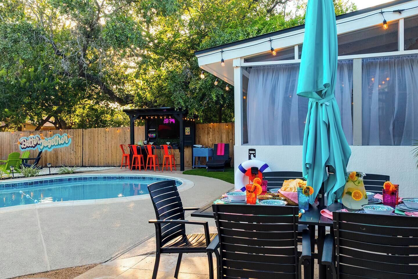Un jardin avec une piscine, un espace salon extérieur et une terrasse couverte.