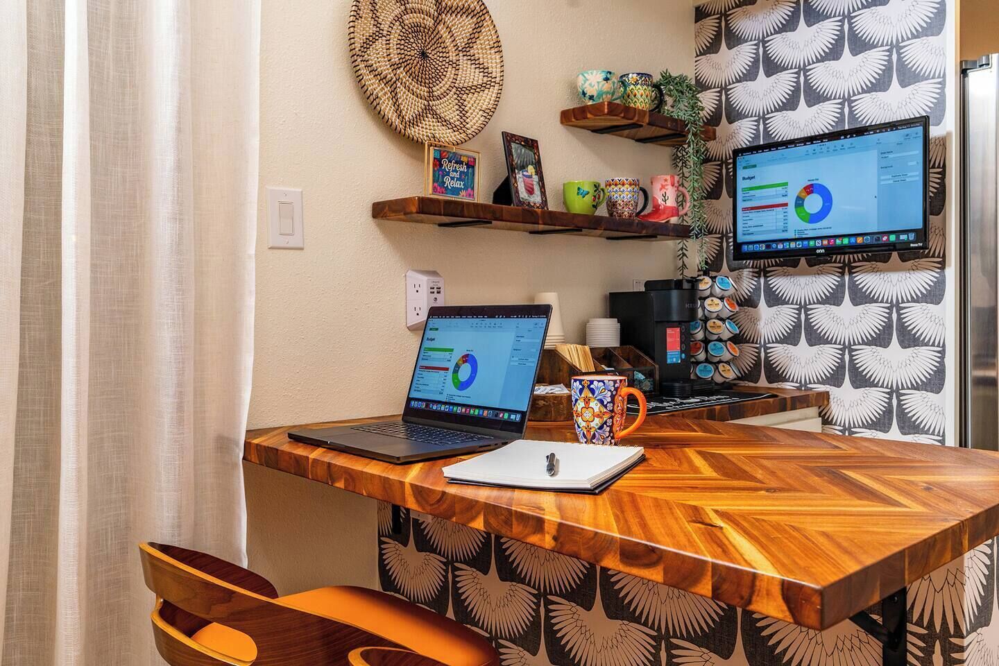 A wooden desk with two laptops, a coffee machine, and a mug.