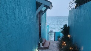 A pathway leading to a balcony with a view of the sea, a blue wall, and decorative lights. - Waterfront Home 3BR - Swim & Snorkel from Patio (Nassau)