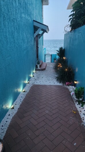 A pathway leading to a balcony with a view of the sea, a blue wall, and decorative lights. - Waterfront Home 3BR - Swim & Snorkel from Patio (Nassau)