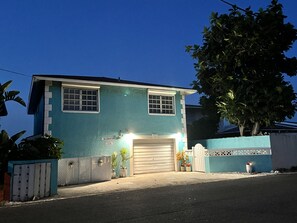 Ein zweistöckiges Haus mit Garage, einem eingezäunten Garten und einem Baum.