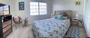 Ein Schlafzimmer mit Bett, Stuhl, Kommode, Fenster und einem Bild an der Wand.