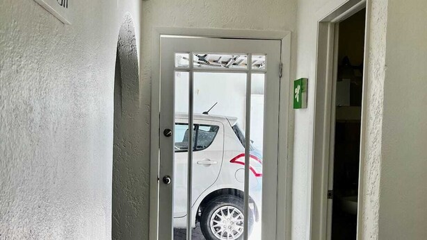 Un corridoio con una porta bianca che dà su un'area di parcheggio.