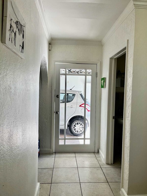A hallway with a white door leading to a parking area. - Waterfront Home 3BR - Swim & Snorkel from Patio (Nassau)
