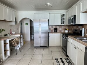 Una cocina moderna con armarios blancos, un refrigerador de acero inoxidable, un microondas y una estufa a gas.