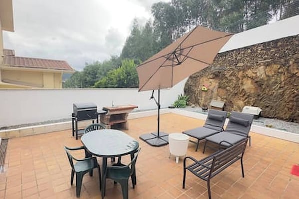 An outdoor patio with a table, chairs, a sofa, and a large umbrella. - Charming 3-bedroom House Rental in Trofa, Portugal (Trofa)