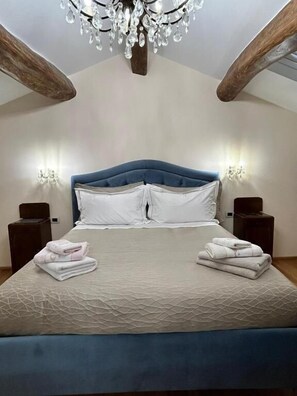 A bedroom with a bed, a chandelier, and two wall-mounted lamps.