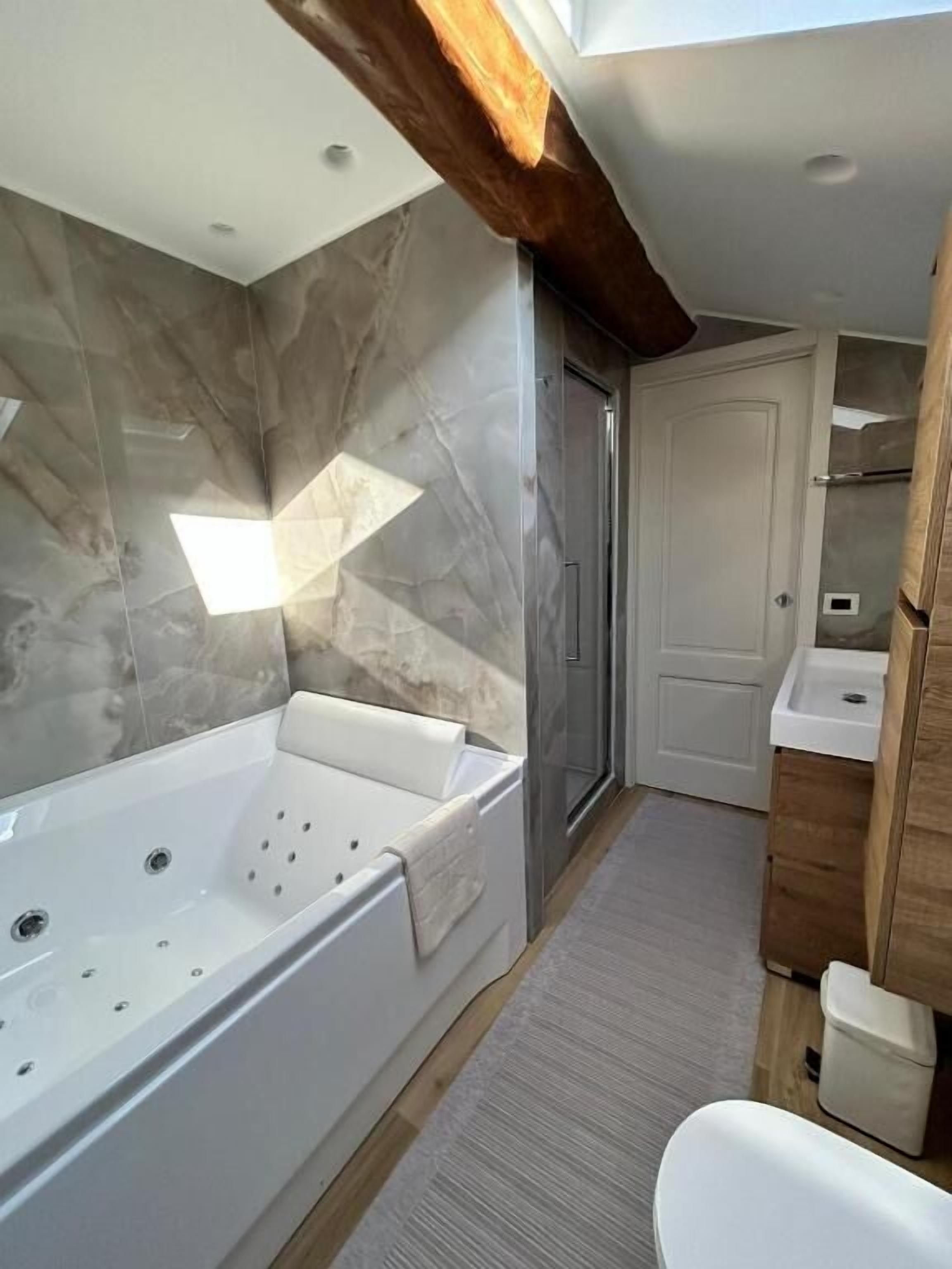 Un bagno moderno con una grande vasca, una doccia e un mobile lavabo con specchio.