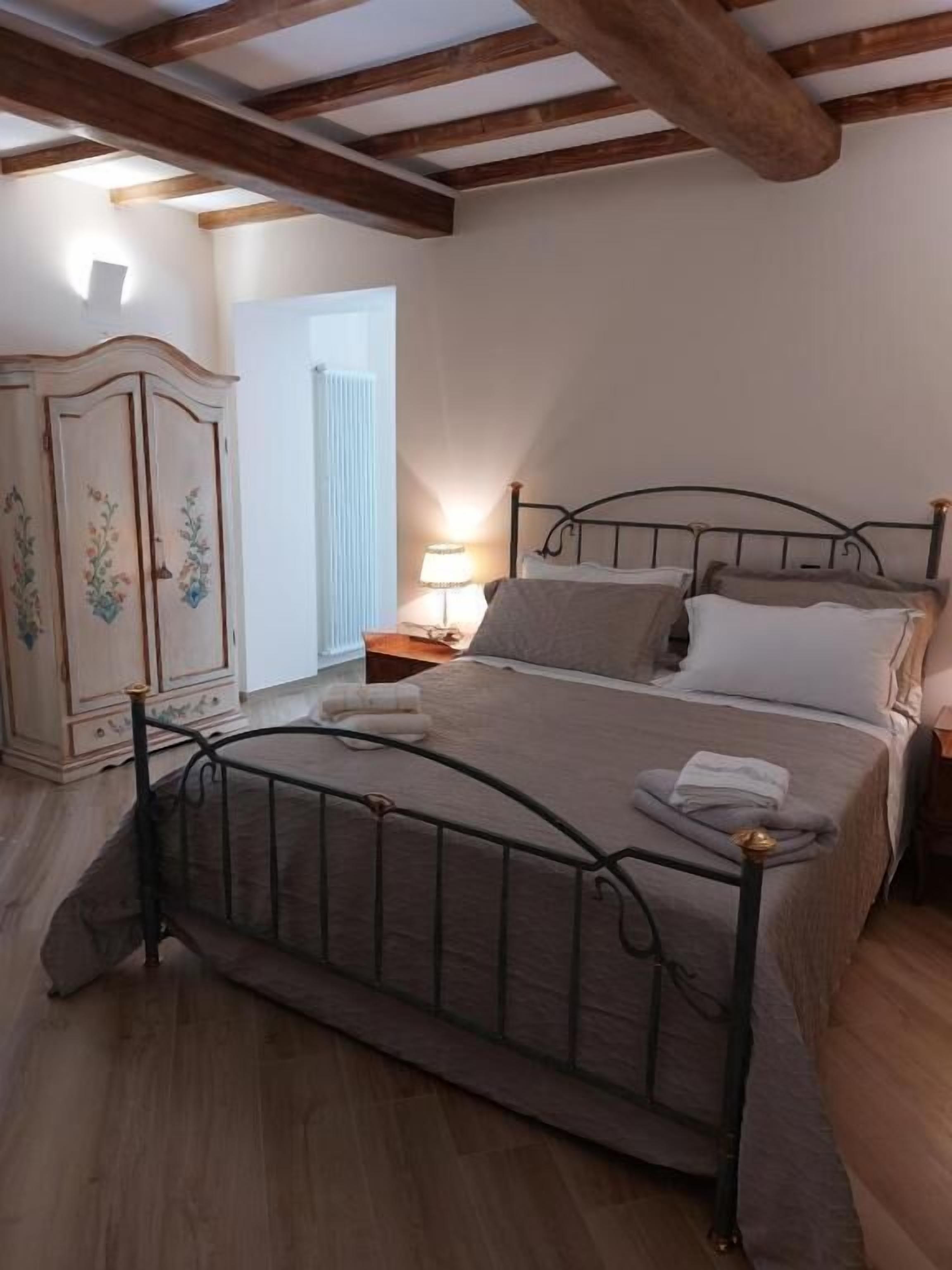A bedroom with a metal bed frame, a wooden wardrobe, and a bedside lamp.