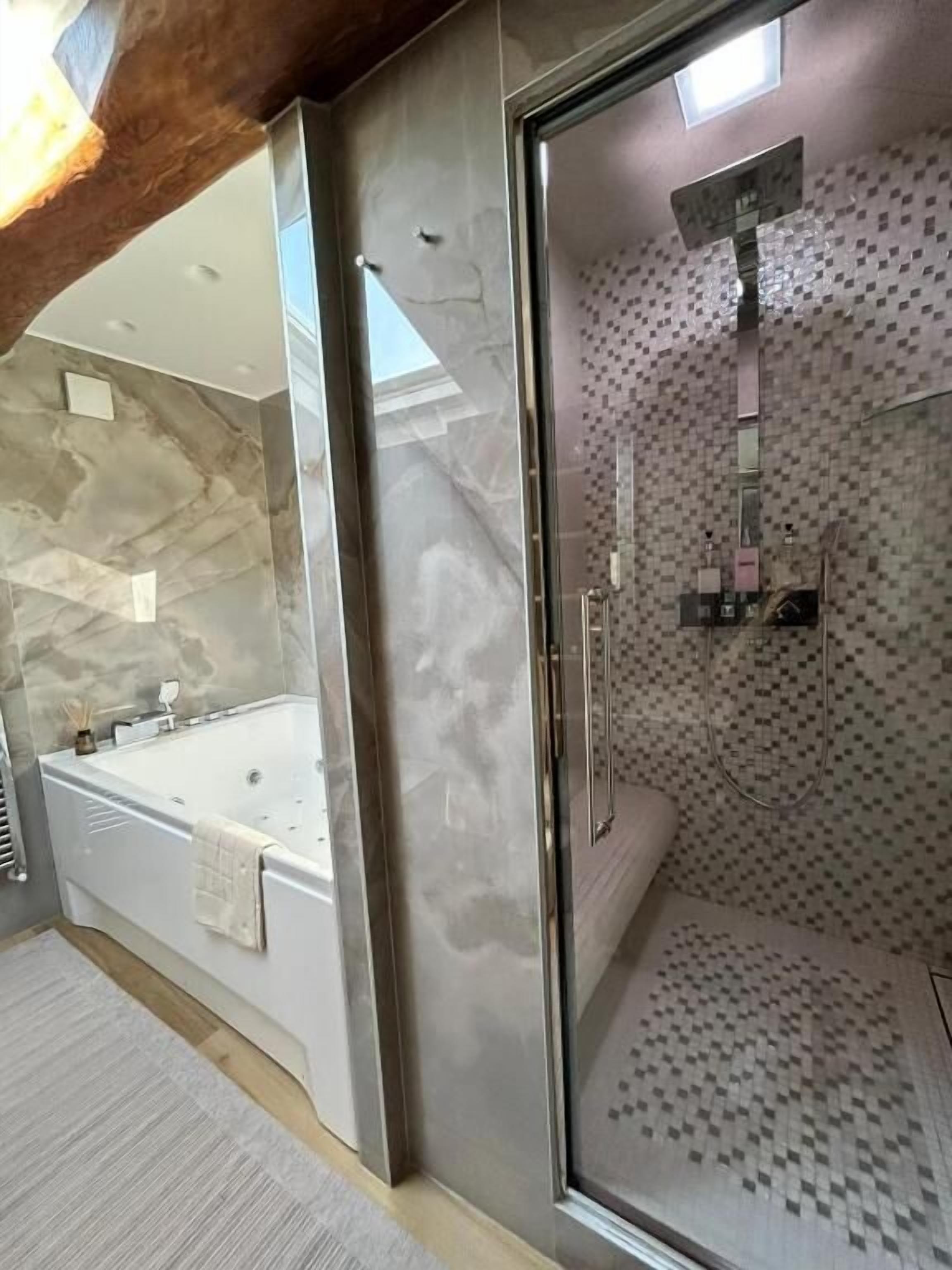 Ein modernes Badezimmer mit einer gläsernen Duschkabine, einer freistehenden Badewanne und einer Marmorwand.