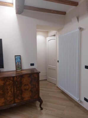 A hallway with a wooden cabinet, a radiator, and a door leading to another room.