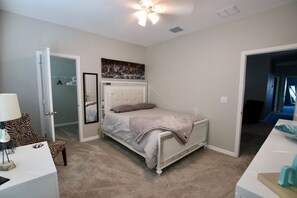 A bedroom with a bed, a chair, a desk, and a ceiling fan. - Spacious 4-bedroom house with pool and gym access not far from beaches! (Palmetto)