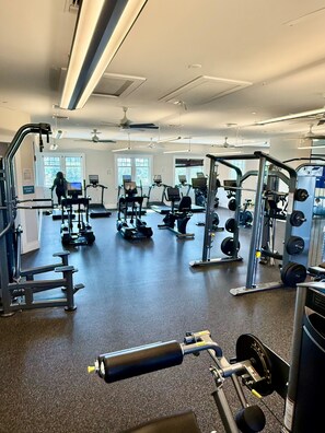 Ein Fitnessstudio mit verschiedenen Trainingsgeräten, darunter Laufbänder, Kraftgeräte und Kurzhanteln.