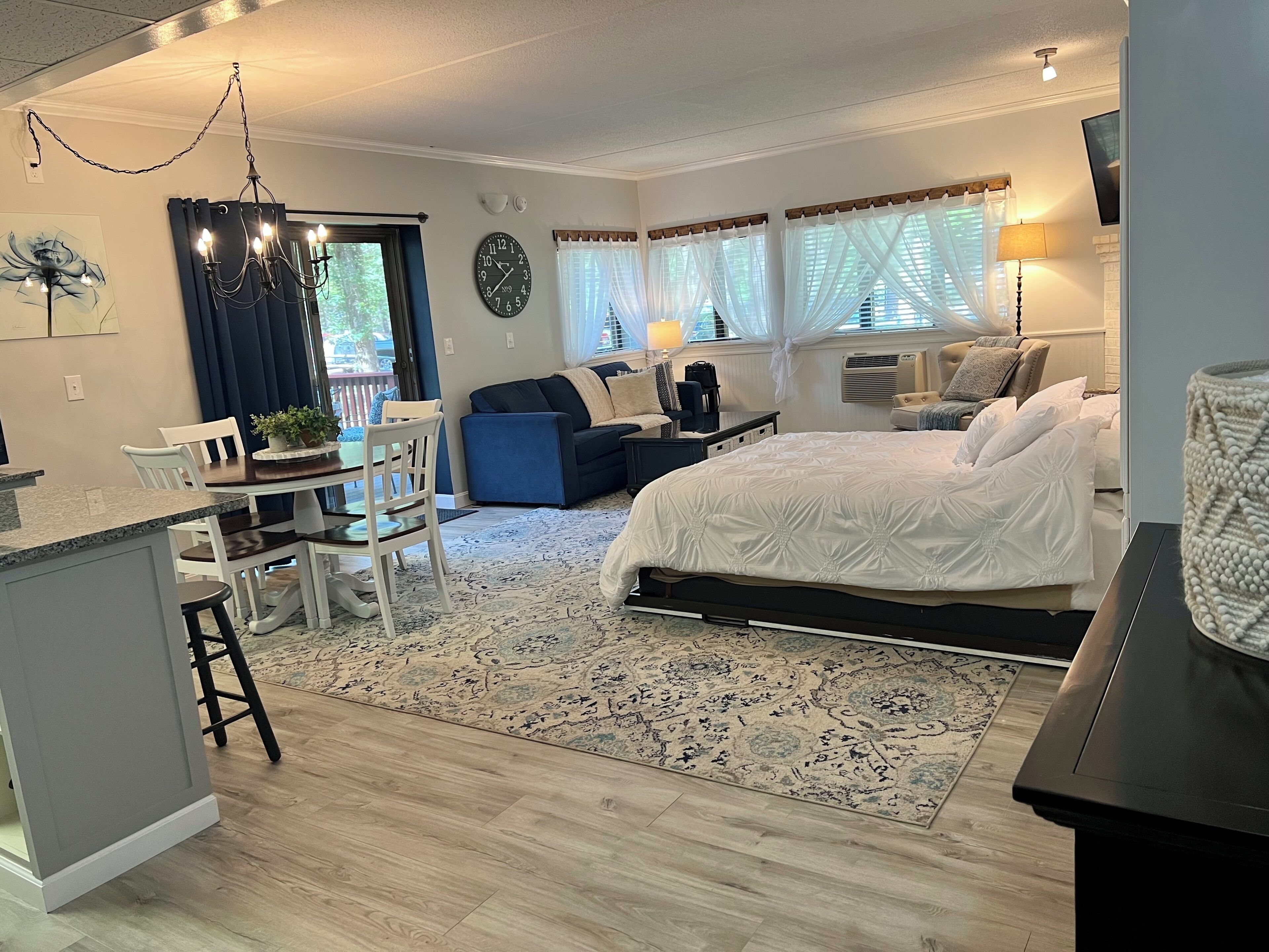 A modern bedroom with a large bed, a desk, and a dining area.