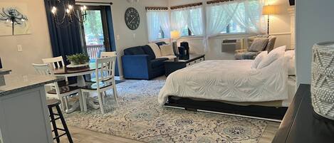 A modern bedroom with a large bed, a desk, and a dining area.