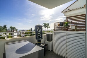 Eine Dachterrasse mit Grill, Mülleimer und weißer Brüstung.