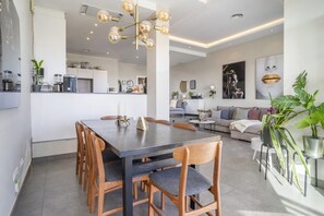 Eine moderne Küche mit Essbereich, ein Wohnzimmer mit Sofa und ein Esstisch mit Stühlen.