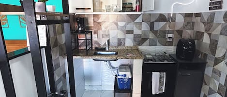 Una cocina compacta con un lavamanos, una cafetera y una pequeña encimera.
