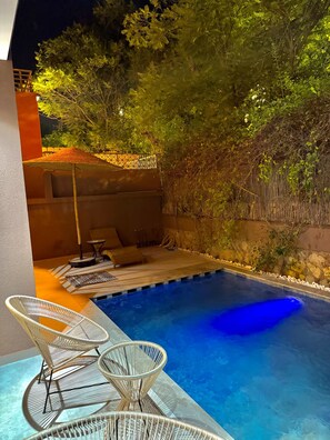A swimming pool with a clear blue water surface, surrounded by a wooden deck and a bamboo fence. - Gym, Heated Private Pool, Sunlit Terrace, Private Garden & free Parking (Marrakesh)