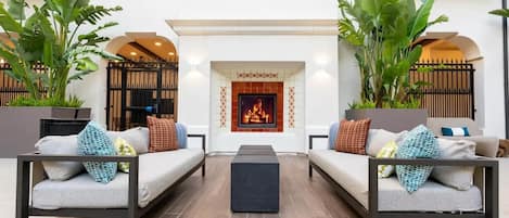 A modern outdoor seating area with two sofas, a central coffee table, and a fireplace.