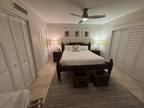 Een slaapkamer met een bed, nachtlampen, een plafondventilator en een vloerkleed.