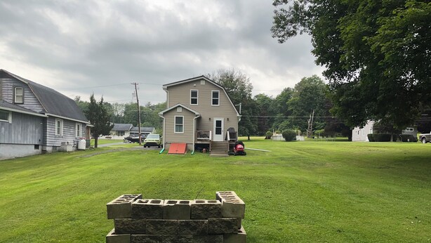 A residential area with a house, a lawn, and a stack of stone blocks.