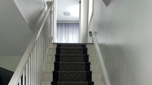 A staircase with a patterned carpet and white railings leading to a landing.