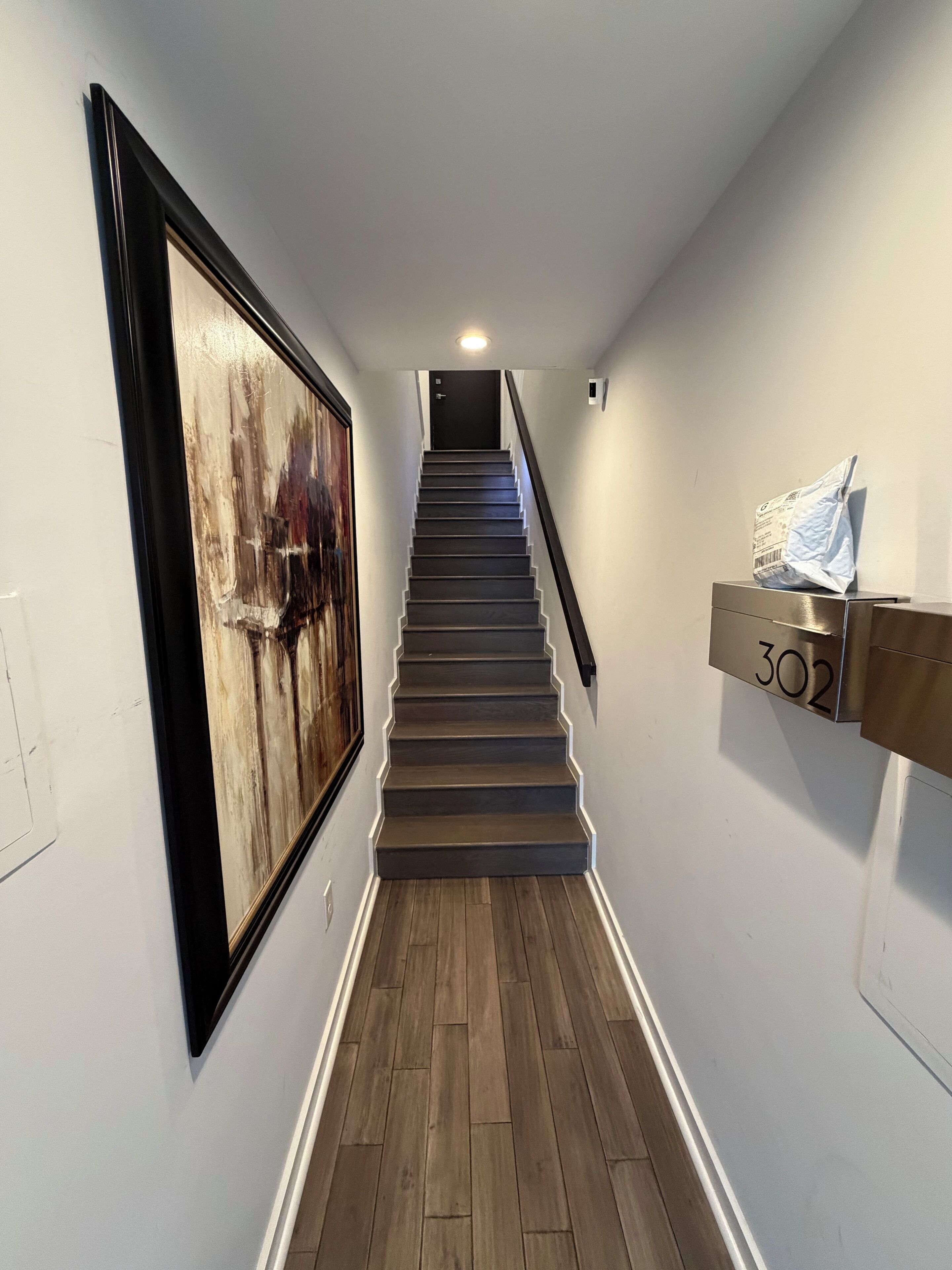 A staircase with wooden steps and a black handrail, leading to a door at the top.