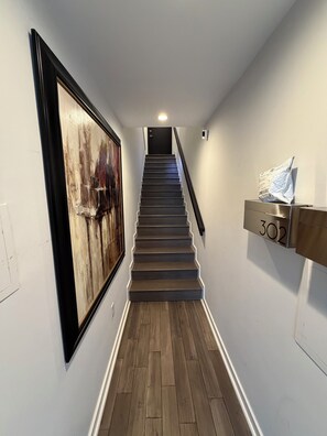 A staircase with wooden steps and a black handrail, leading to a door at the top.