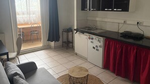 Cozinha compacta com geladeira, pia e micro-ondas. Há uma área de refeições com mesa e cadeiras.