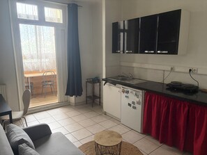 Eine kompakte Küche mit Kühlschrank, Spüle und Mikrowelle. Ein Essbereich mit Tisch und Stühlen vorhanden.