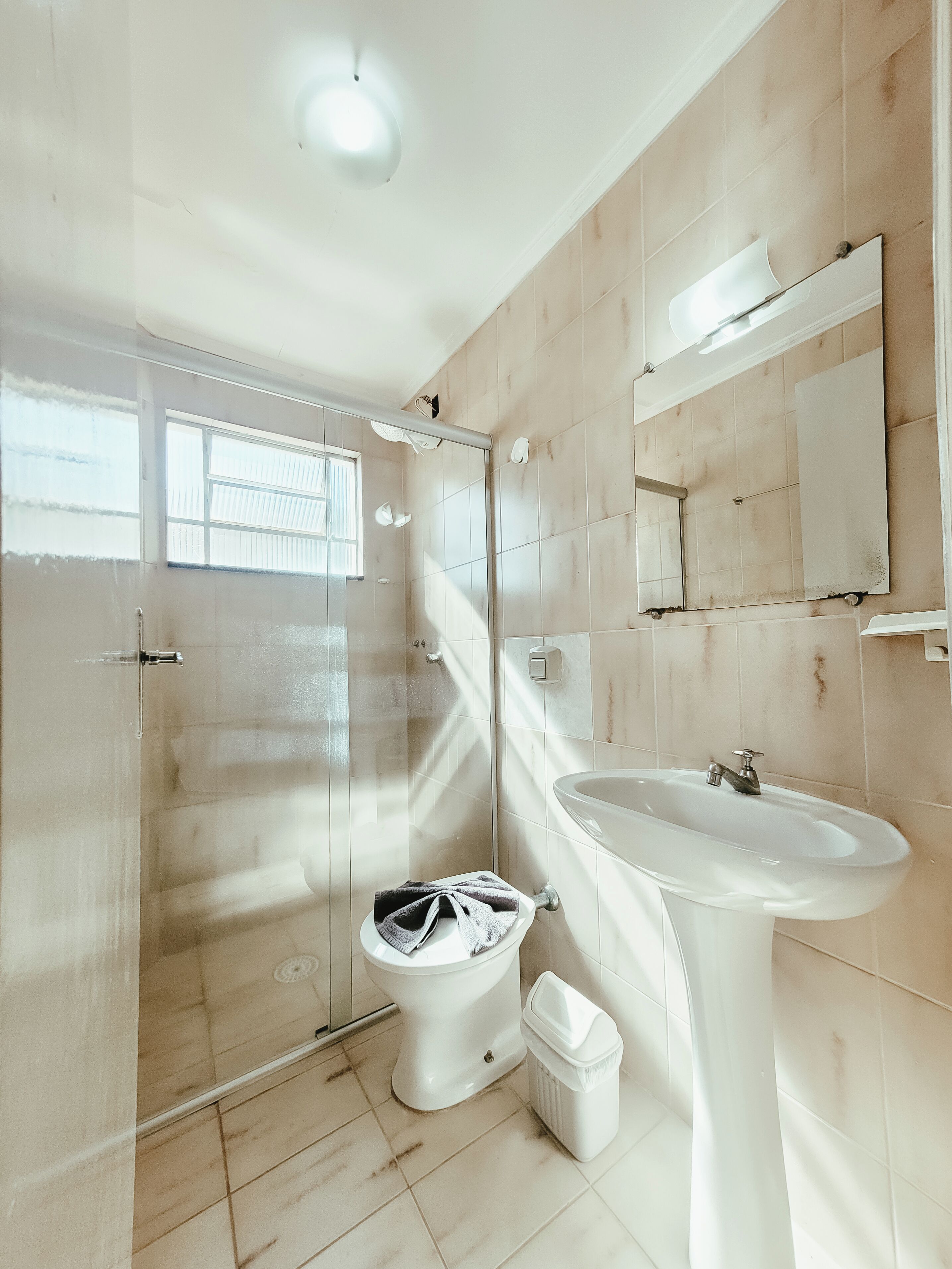 A modern bathroom with a toilet, bidet, sink, and a glass-enclosed shower.