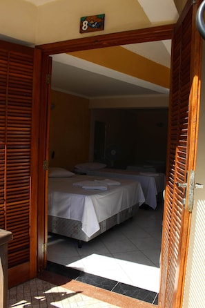 Una habitación de hotel con dos camas, una puerta de madera y un letrero con un número encima.