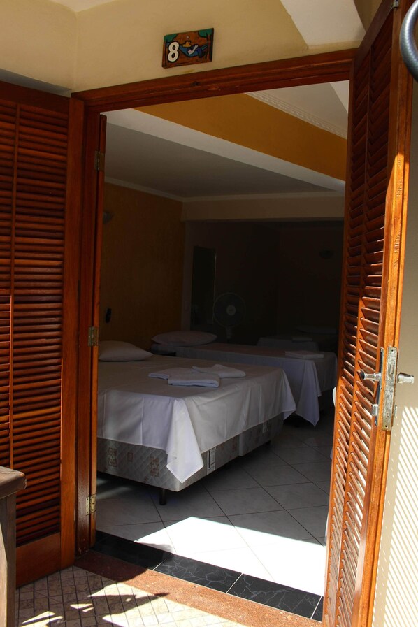 A hotel room with two beds, a wooden door, and a number sign above the door.