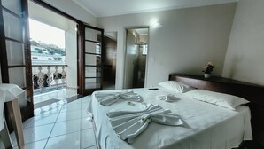 Habitación de hotel con cama, balcón y vistas al exterior.