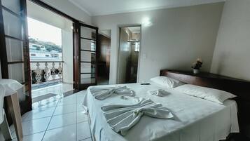 Quarto de hotel com cama, varanda e vista para o exterior.